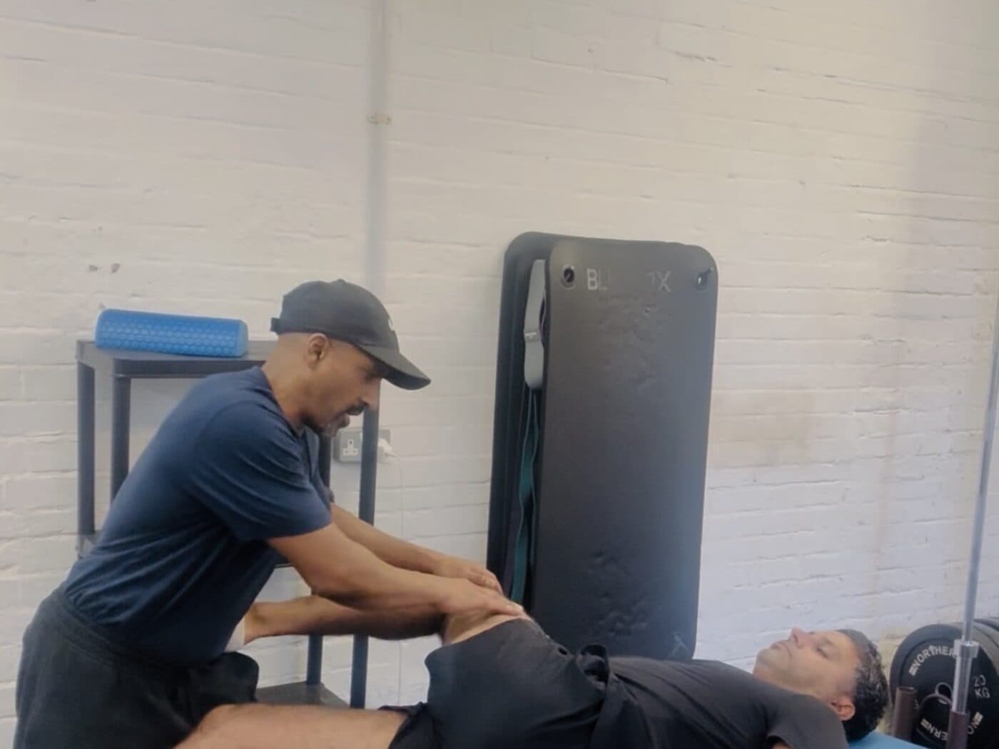 Steve stretching a client's hip on a treatment table in the studio